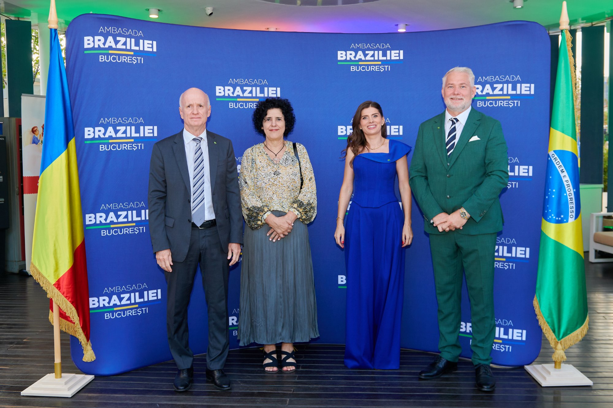 Morten Reimers, at right in a green suit, with three guests between the Romanian and Brazilian flags at Brazil National Day 2026