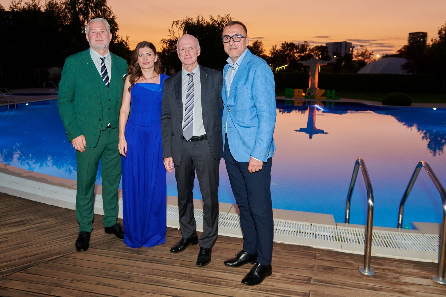 Morten Reimers in a green suit with two guests beside the pool at the Brazil National Day reception